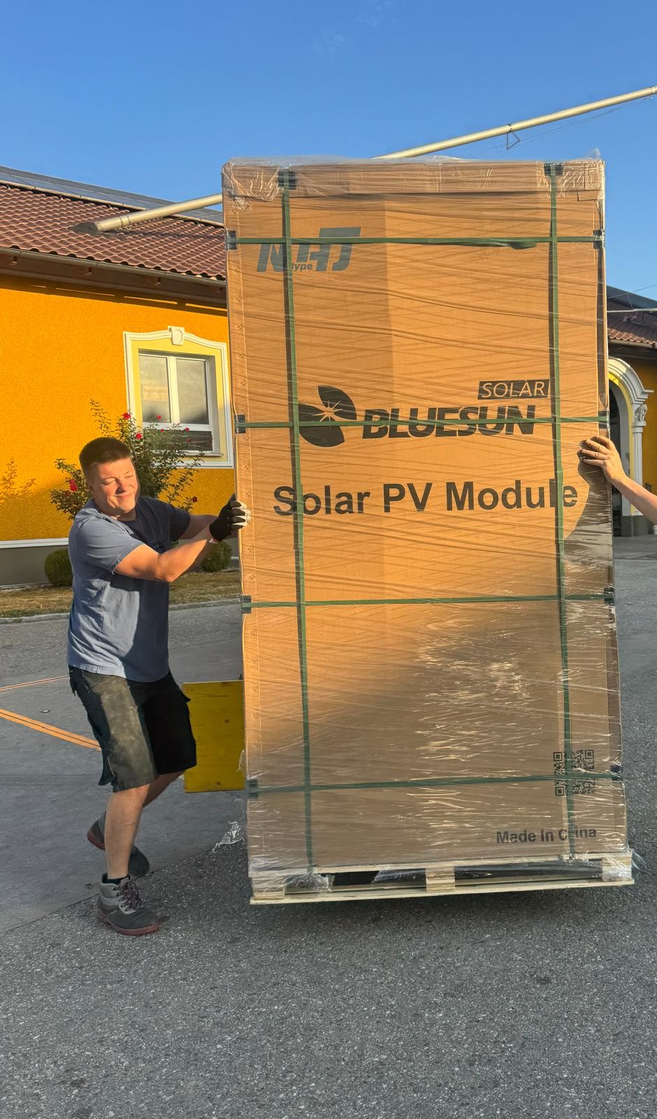 Monteur bewegt eine Palette Bluesun Solarmodule bei der Anlieferung am Hof